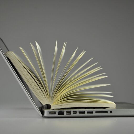 obrazek przedstawia laptop, na którym leży rozłożona książka